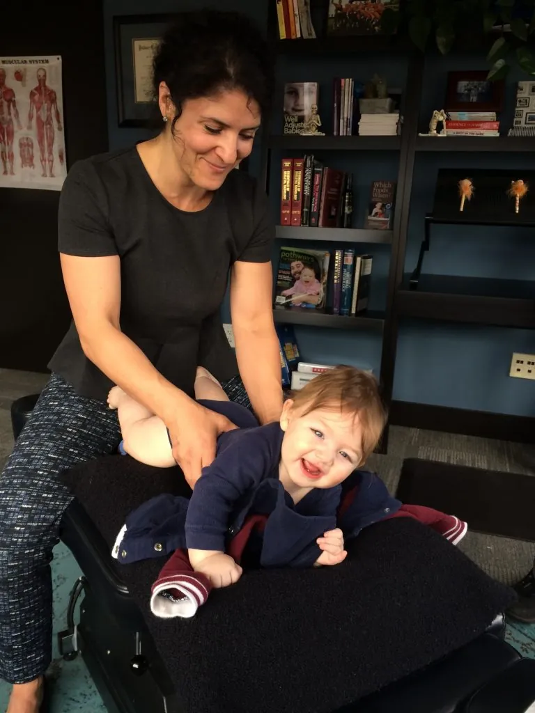 Dr. Xidos gently adjusting a baby lying on a padded table